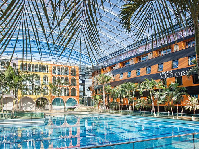 Weitläufiges Wellenbad mit Palmen im Hotel Victory Therme Erding, perfekt für einen entspannten Aufenthalt.